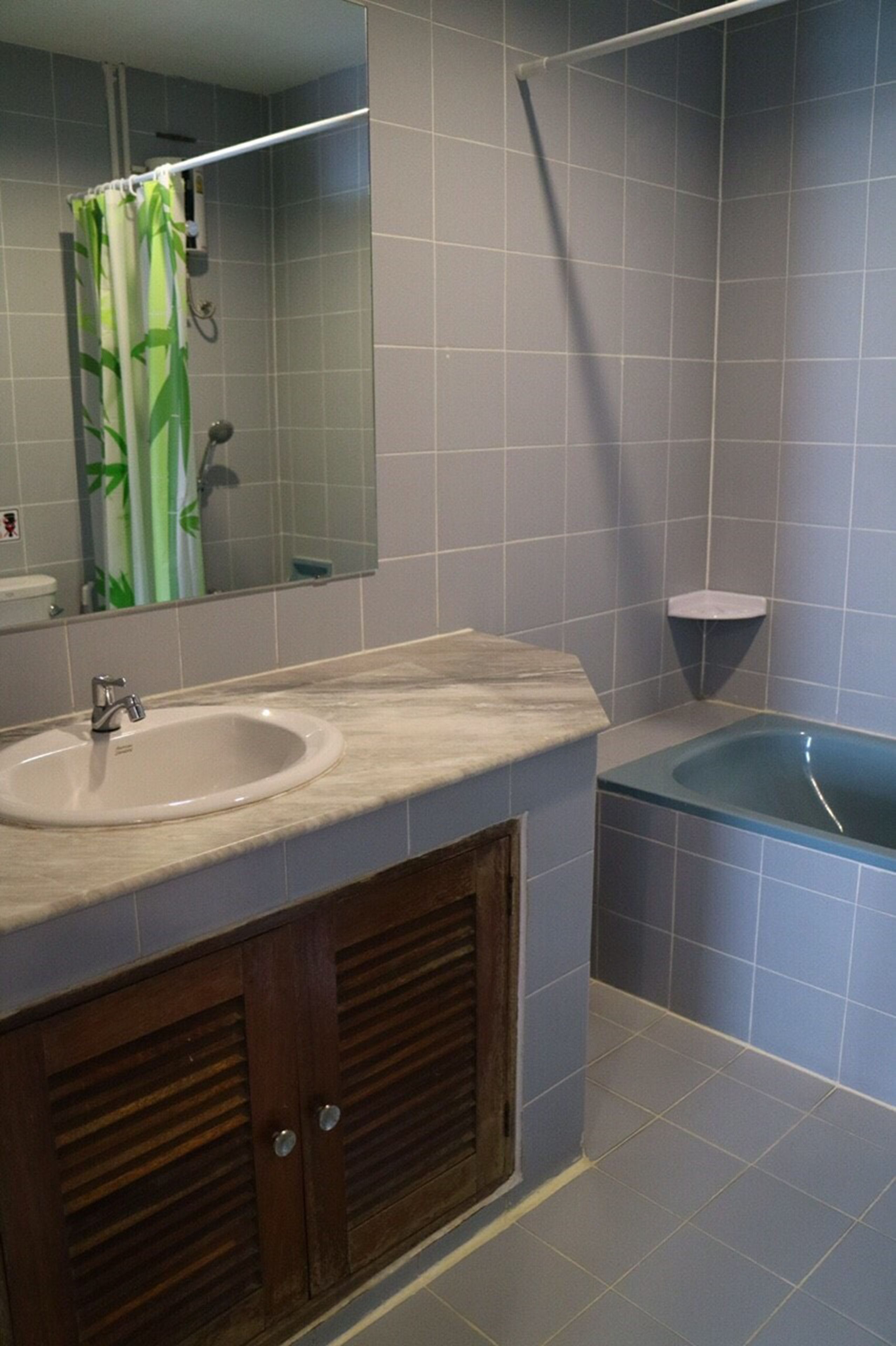 A bathroom with a sink, mirror, shower, and bathtub.