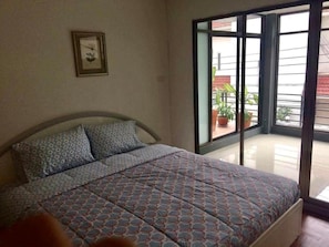 A bedroom with a bed, a window, and a door leading to a balcony. - Nine Place Sukhumvit 46 (Bangkok)