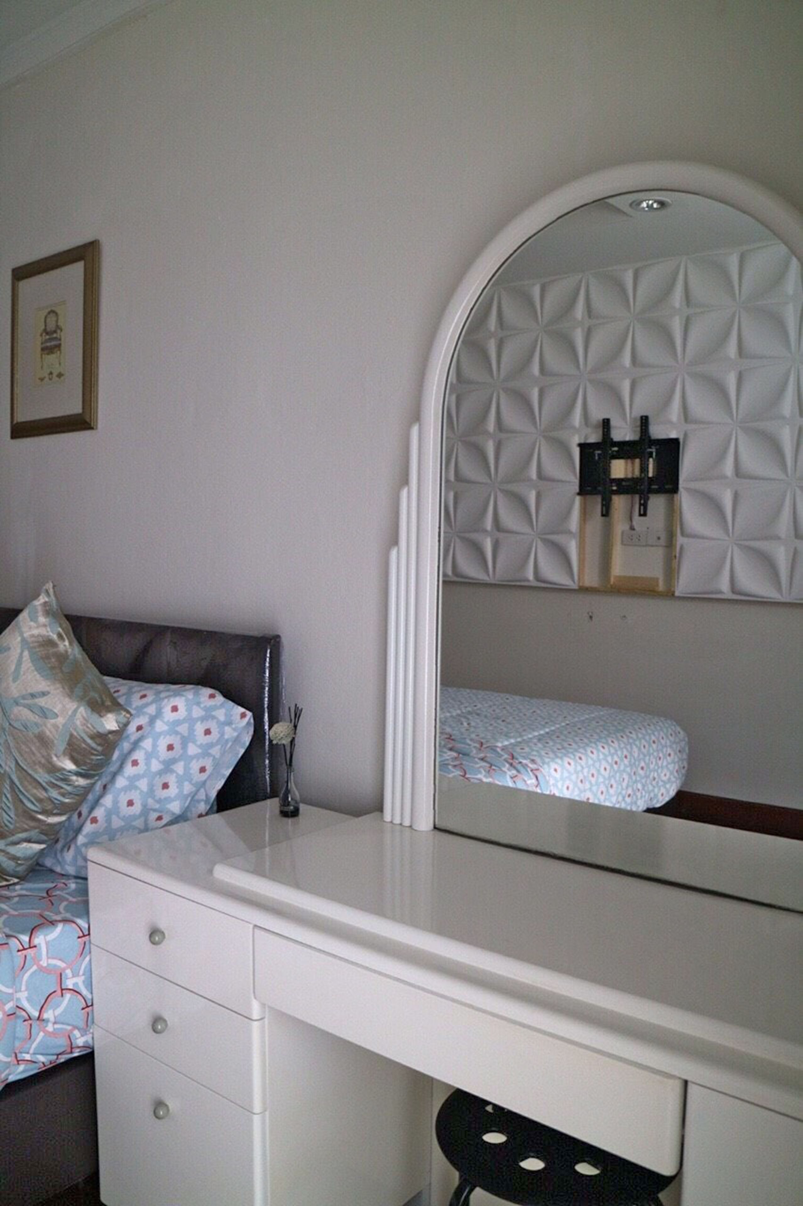 A bedroom with a bed, a dresser, a mirror, and a wall-mounted shelf.