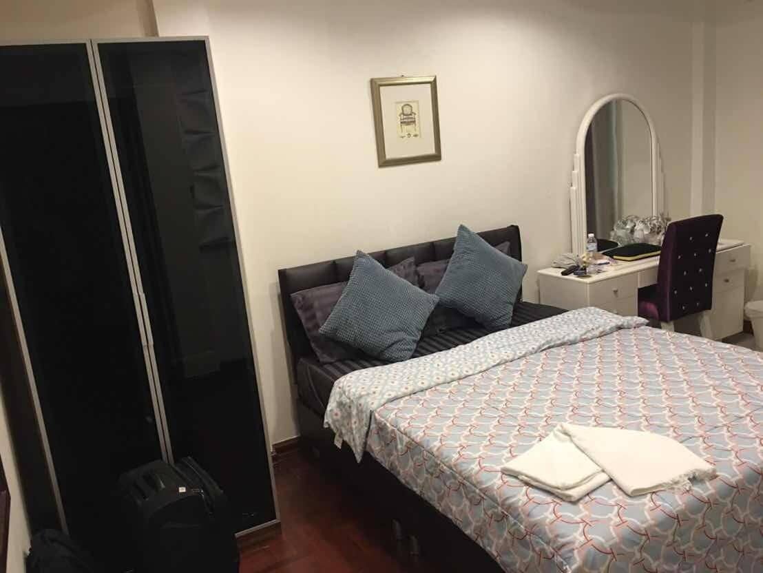 Een slaapkamer met een bed, een bureau, een stoel, een kledingkast en een spiegel.