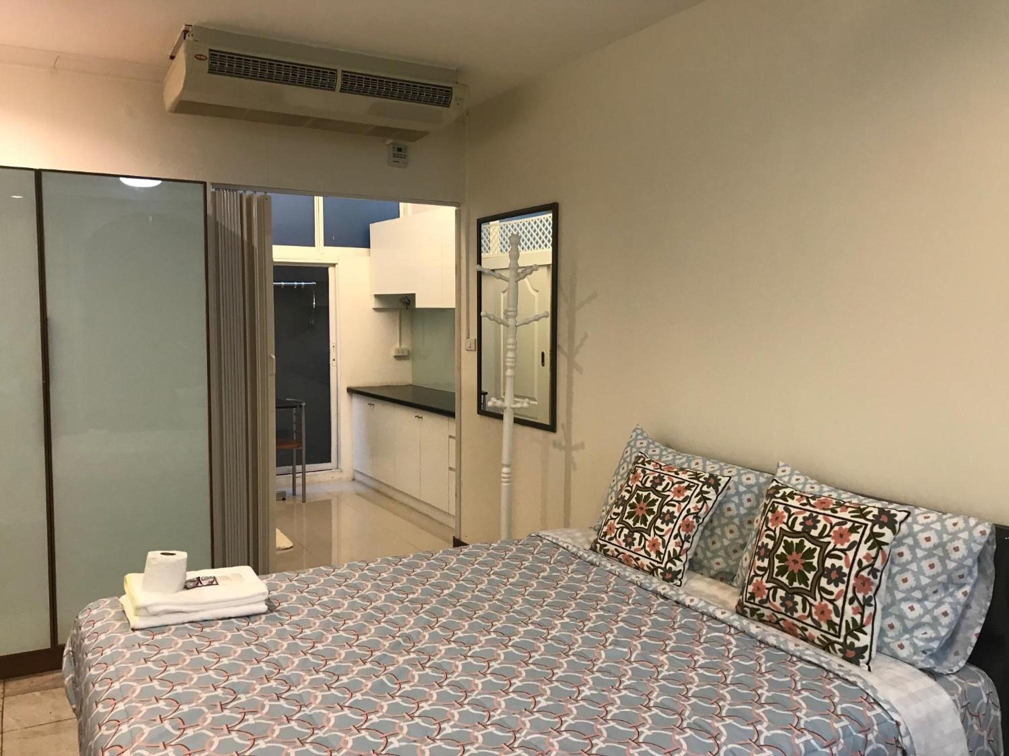 Un dormitorio con cama, armario, espejo y vistas a un balcón.