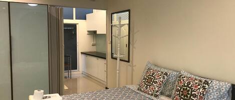 A bedroom with a bed, a wardrobe, a mirror, and a view of a balcony.
