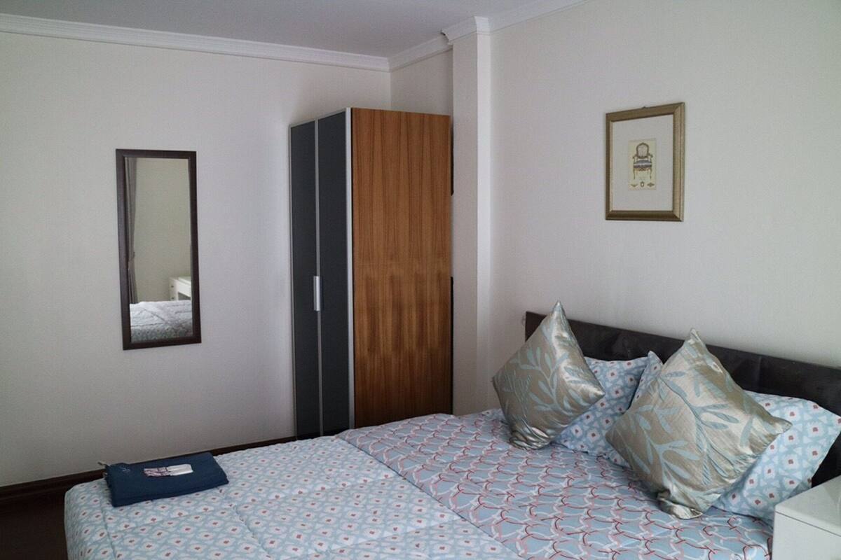 A bedroom with a bed, a wardrobe, a mirror, and a framed picture on the wall.