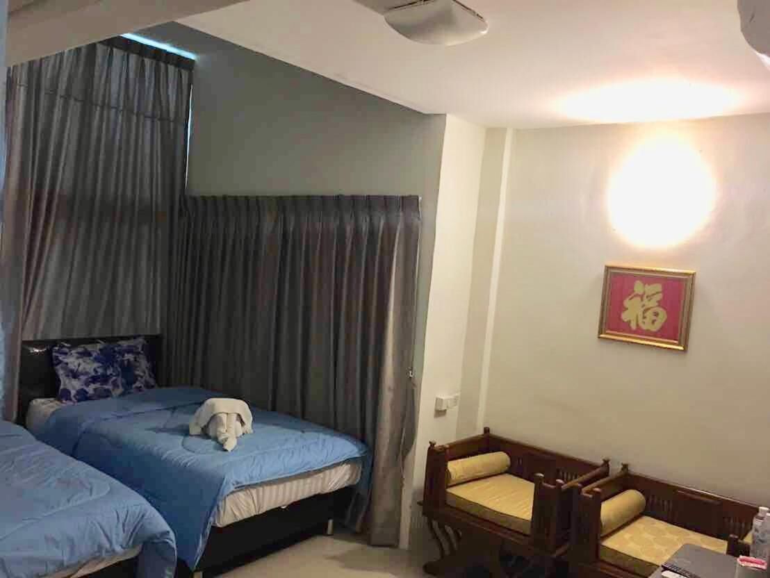 A bedroom with two beds, a wooden chair, and a wall-mounted light fixture.
