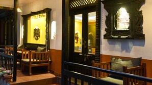 Un vestíbulo de hotel con sillas de madera, una escalera y decoraciones ornamentales en las paredes.