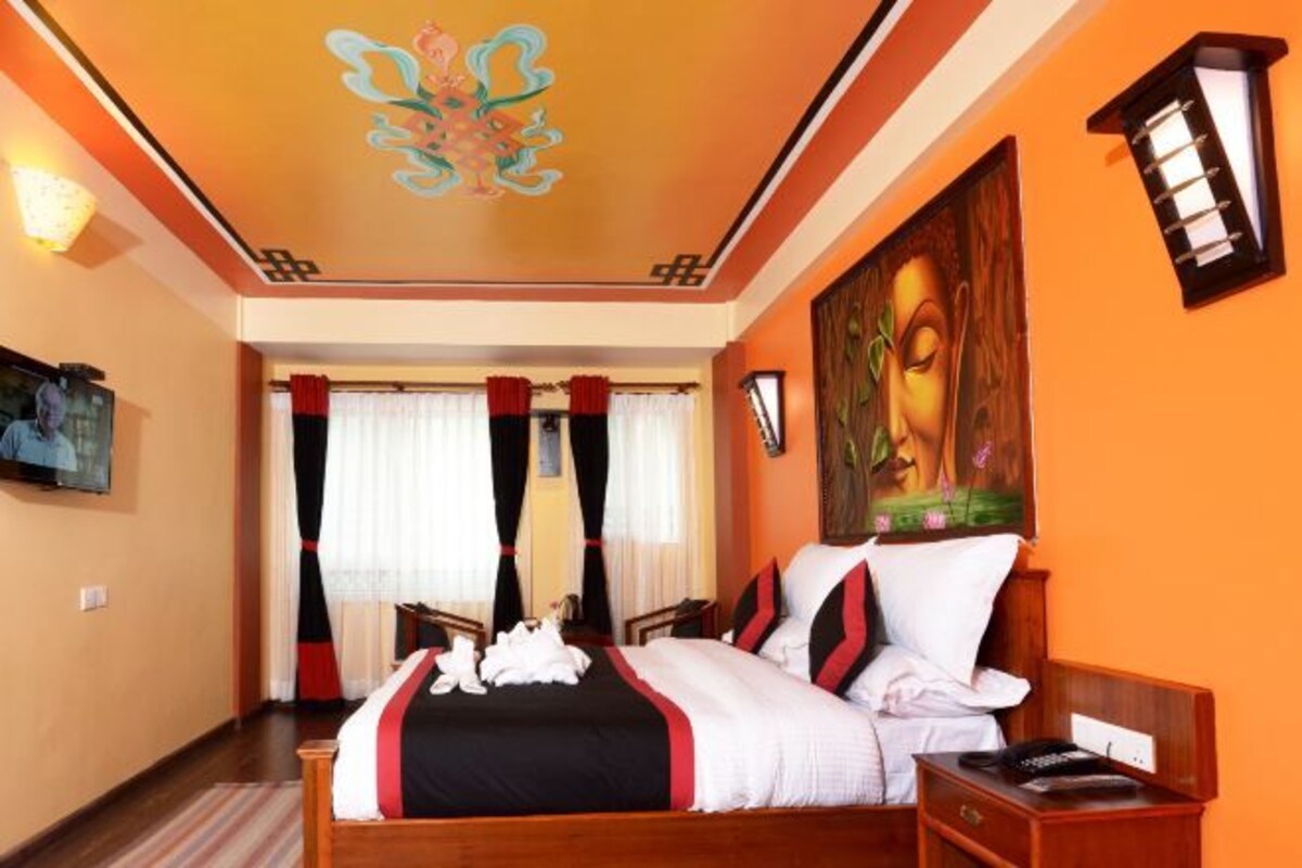 Quarto de hotel com cama, cortinas, um quadro, mesa de cabeceira e teto com design floral.