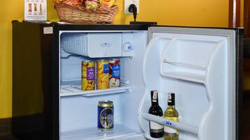 Un minibar con carta, diferentes bocadillos y bebidas, incluyendo latas y botellas.