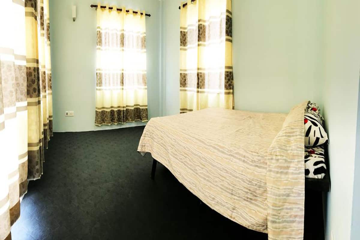 A bedroom with a bed, curtains, and a carpeted floor.