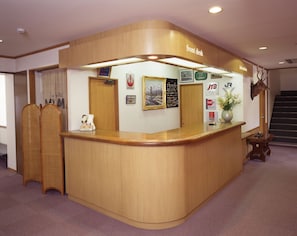 A reception desk with a wooden finish, a cash register, and a sign indicating a 'Front Desk' area. - Inner Village Miyama (Hakuba)