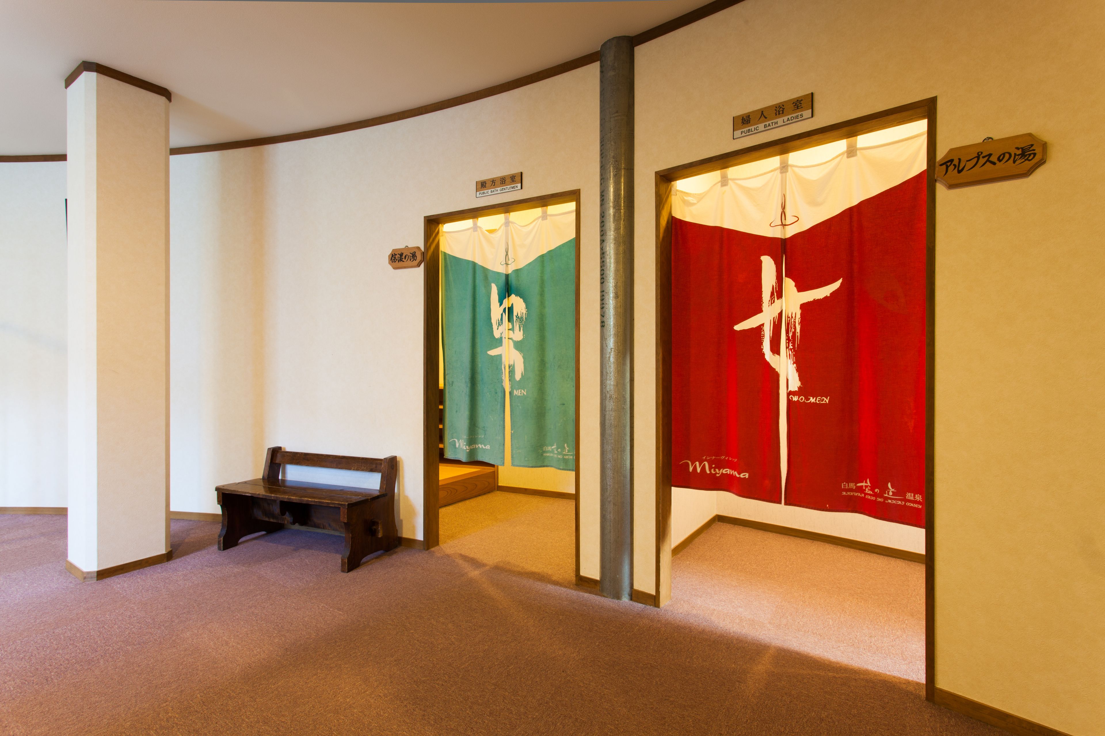 A hallway with a bench, a green banner with white text, and a red banner with white text.