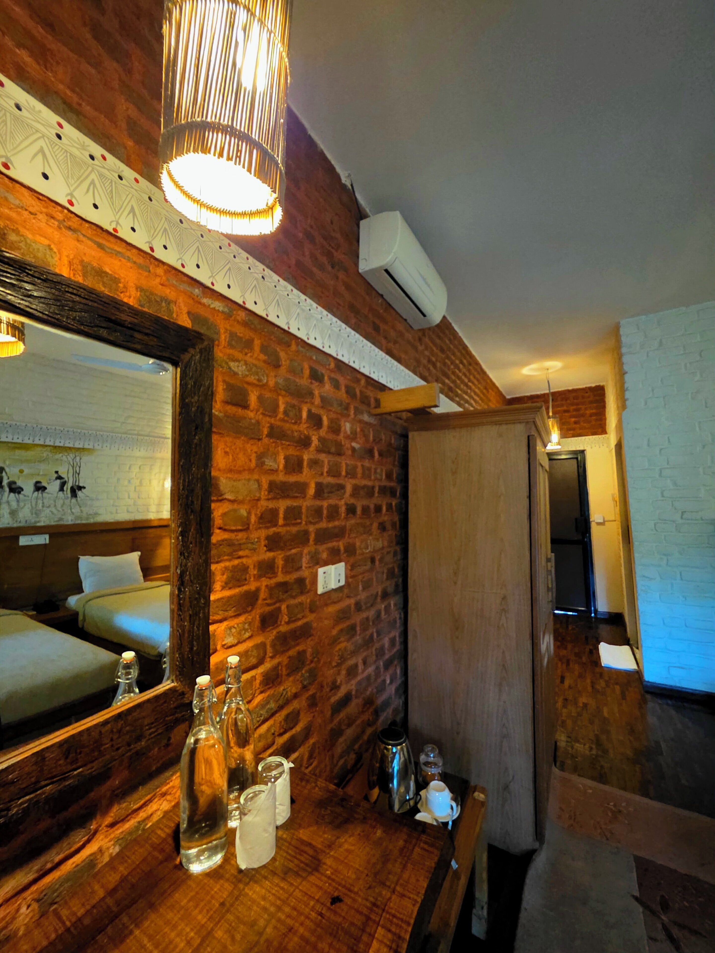 A room with a brick wall, wooden furniture, a mirror, and a hanging light fixture.