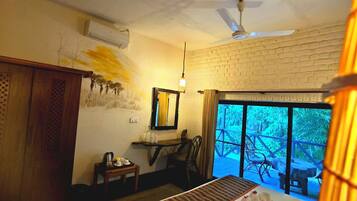 A hotel room with a bed, a desk, a chair, a window with a view, and a ceiling fan.