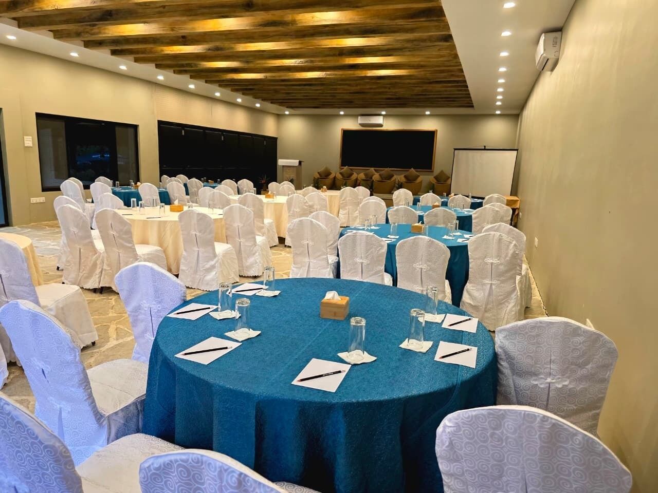 A conference room with round tables, white chairs, and a stage area.