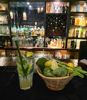 Un bar con bebidas e ingredientes frescos sobre la barra.