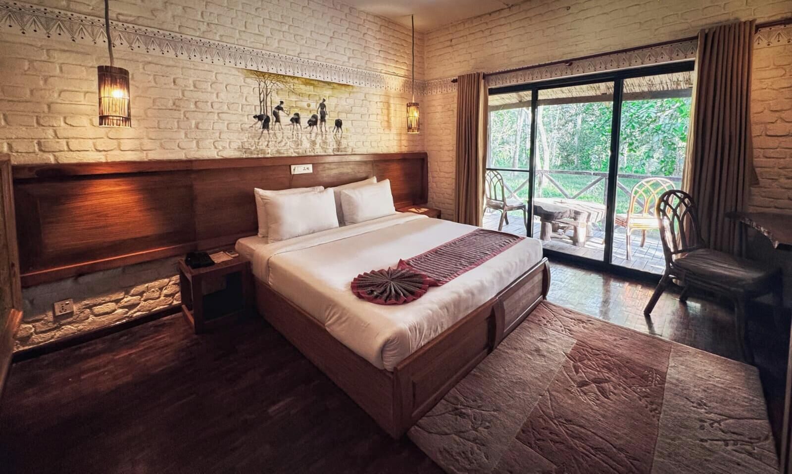 A bedroom with a large bed, a wooden headboard, a stone floor, and a view of the outdoors through a glass door.