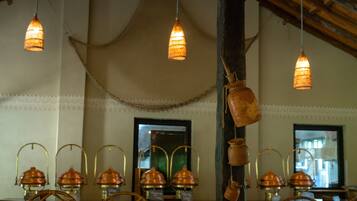 L’intérieur d’un restaurant, avec des luminaires suspendus, des casseroles en cuivre et des meubles en osier.