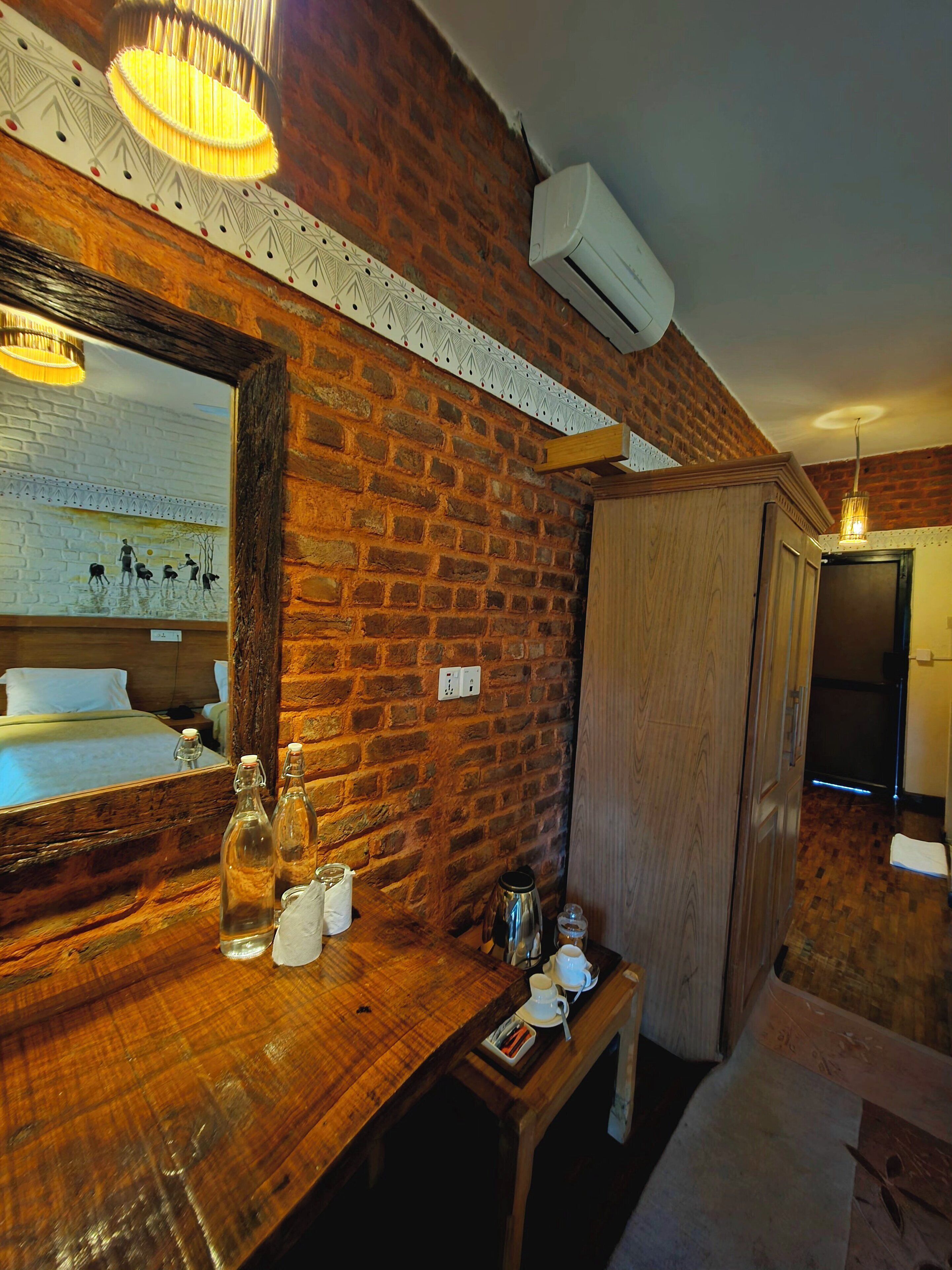 Habitación de hotel con pared de ladrillo, muebles de madera, un espejo grande y una cama.