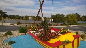 A colorful boat-shaped planter with flowers, a wooden fence, and a lake in the background.