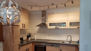 A modern kitchen with wooden cabinets, a stainless steel oven, a dishwasher, and a built-in sink. - Vacation Bungalow Bergblüte It is awarded with 4 **** (Bad Harzburg)