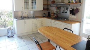 A kitchen with white cabinets, a wooden table, and a window. - Villa with floor and garden (Le Thoronet)