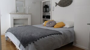 Une chambre à coucher avec un lit, une cheminée, une étagère remplie de livres et un décor mural représentant des poissons.