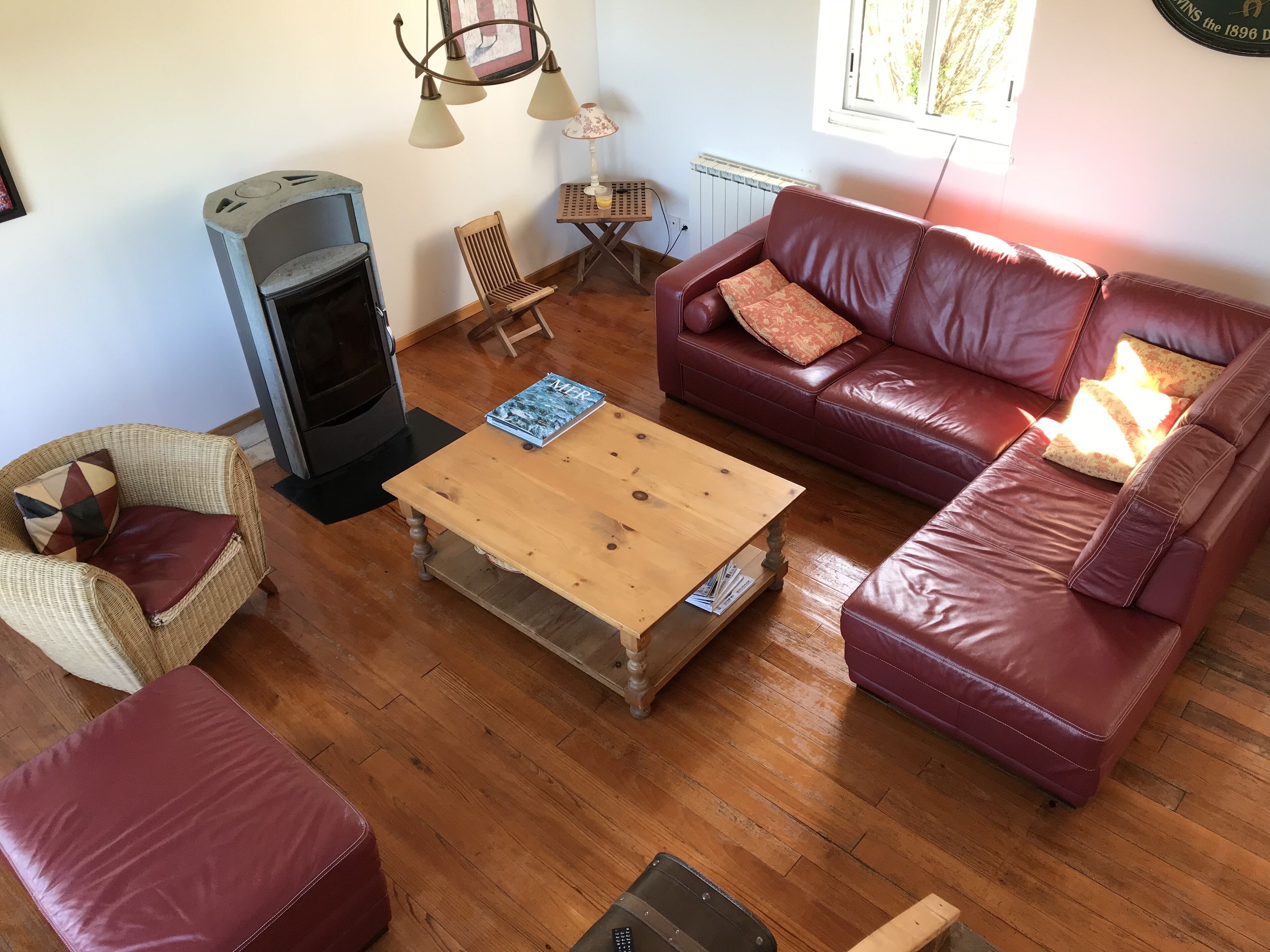 Un salon chaleureux avec une cheminée, un canapé en cuir, une table basse en bois et des fauteuils en osier.