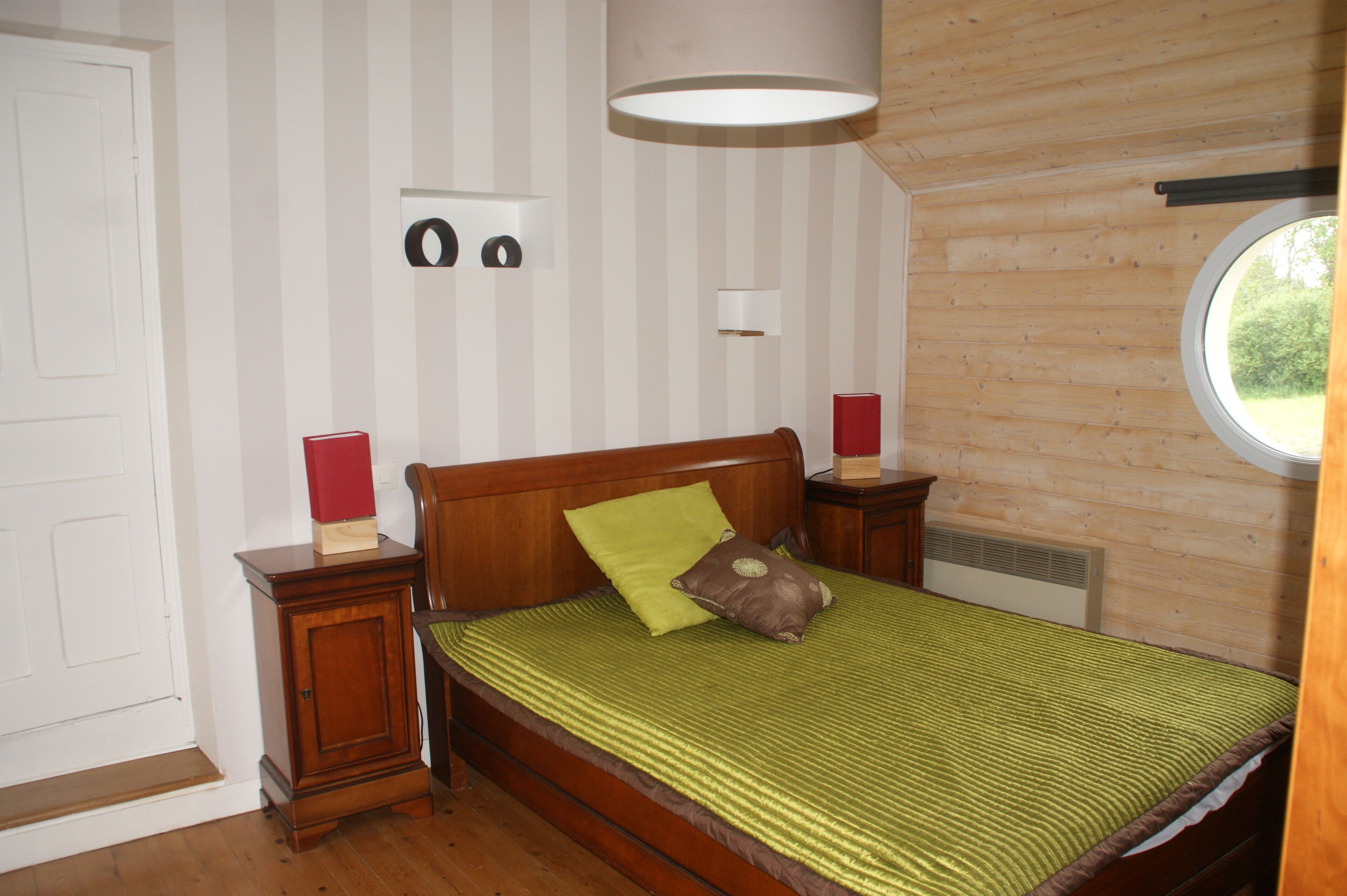 A bedroom with a wooden bed, a nightstand, a bedside table, a window, and a door.