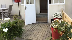 A small, open-sided structure with a wooden deck, a red umbrella, and potted plants with white and pink flowers. - HOUSE SEA VIEW 100M BEACHES WITH ENCLOSED GARDEN (Trédrez-Locquémeau)