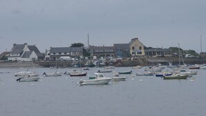 A harbor with multiple boats docked and a row of buildings along the shore. - HOUSE SEA VIEW 100M BEACHES WITH ENCLOSED GARDEN (Trédrez-Locquémeau)