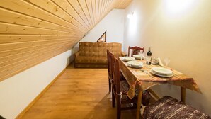 Ein Essbereich mit Holzboden, einer Couch und einem Tisch für zwei Personen.