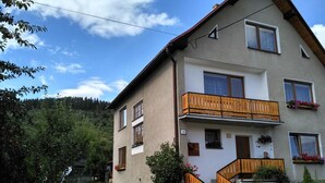 Ein zweistöckiges Haus mit Balkon, Treppe und einem umzäunten Garten.