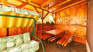 Eine Holzhütte mit einer Bank und einem Sofa, einem Tisch und einer Hängelampe.