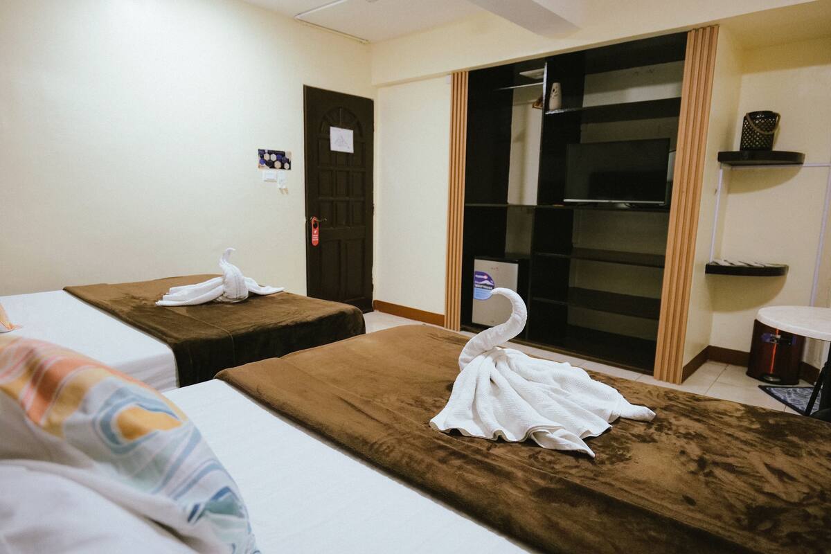 Ein Raum mit zwei Massageliegen, einem Fernseher und einem Schiebetürenschrank.
