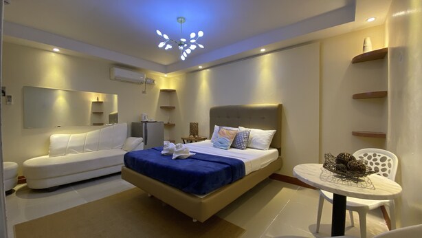Ein modernes Hotelzimmer mit einem Bett, einer Couch, einem kleinen Tisch und einem Sessel.