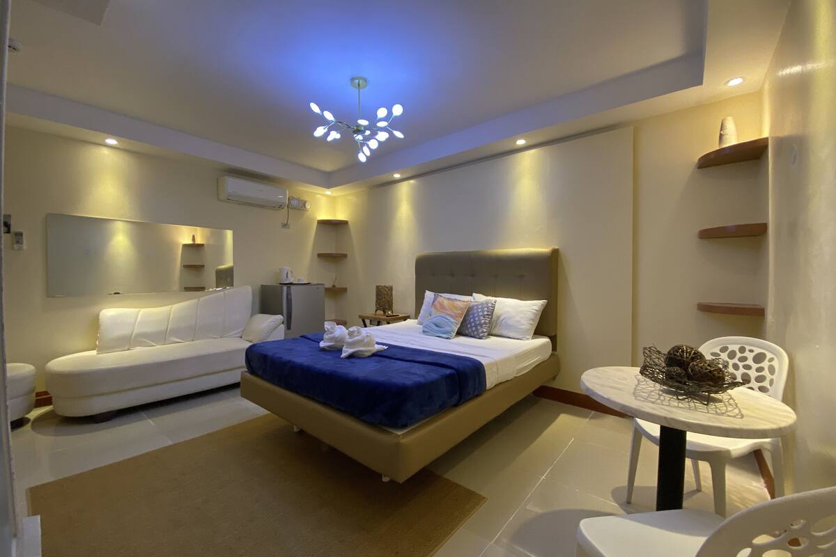 Ein modernes Hotelzimmer mit einem Bett, einer Couch, einem kleinen Tisch und einem Sessel.