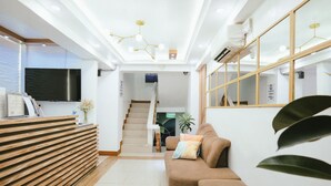 Ein Empfangsbereich mit einem Holzbüro, einem braunen Sofa und einer Treppe im Hintergrund.