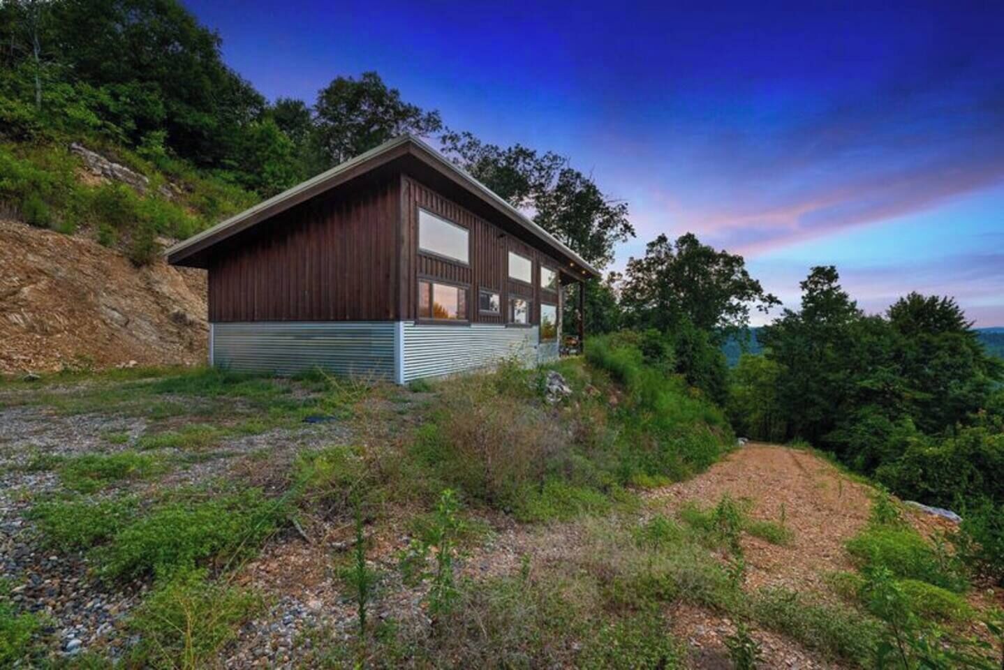 A modern house with a sloped roof, large windows, and a metal siding exterior.