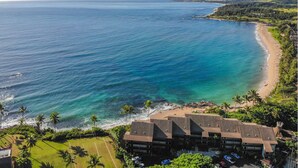 Un hotel sulla spiaggia con diversi edifici, una spiaggia sabbiosa e vista sull'oceano.