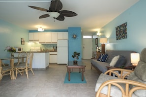 A spacious living area with a dining table, chairs, a sofa, and a ceiling fan.
