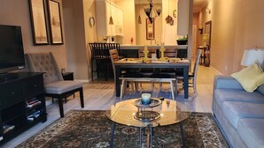A living room with a sofa, TV, and a dining area with chairs and a table.