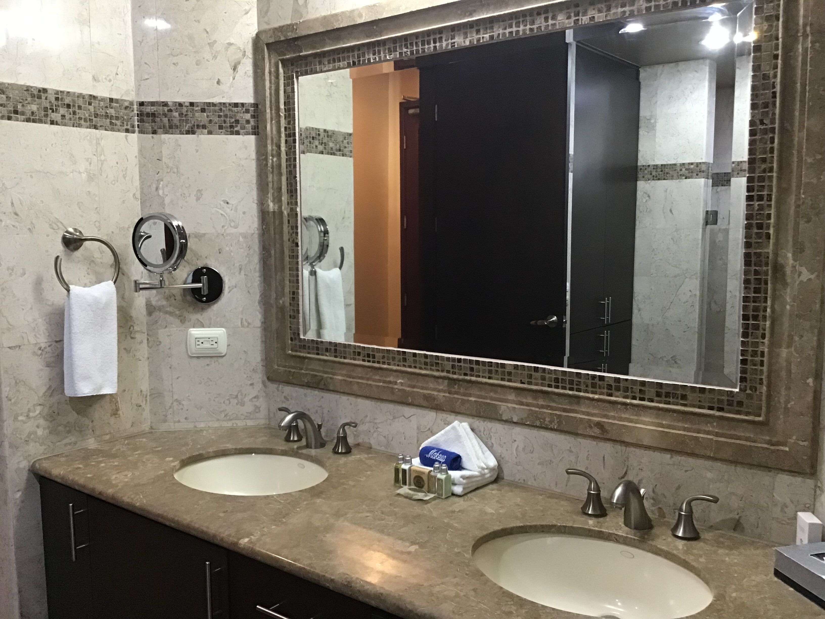 Une salle de bain avec deux lavabos, un grand miroir et un porte-serviettes.