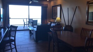 A dining area with a table and chairs, a sofa, and a lamp.