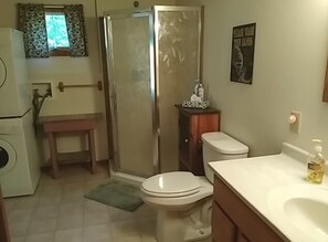 Une salle de bain équipée d’une douche, de toilettes, d’un lavabo et d’une petite table.