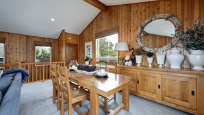 Ein Essbereich aus Holz mit Tisch und Stühlen, einem großen Spiegel und einem Fenster mit Blick auf Grünflächen.
