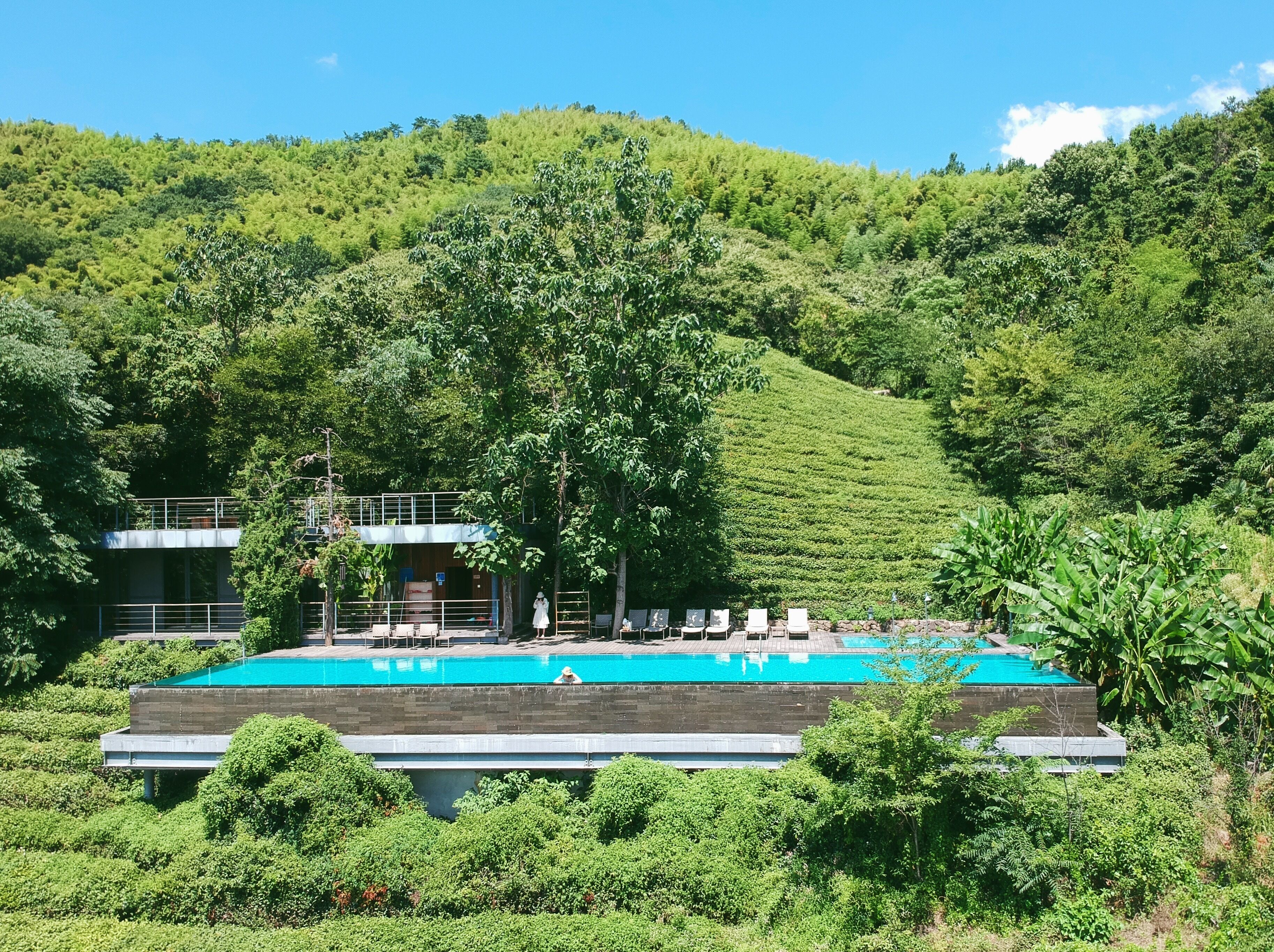 A pool area with a view of a lush green hillside.