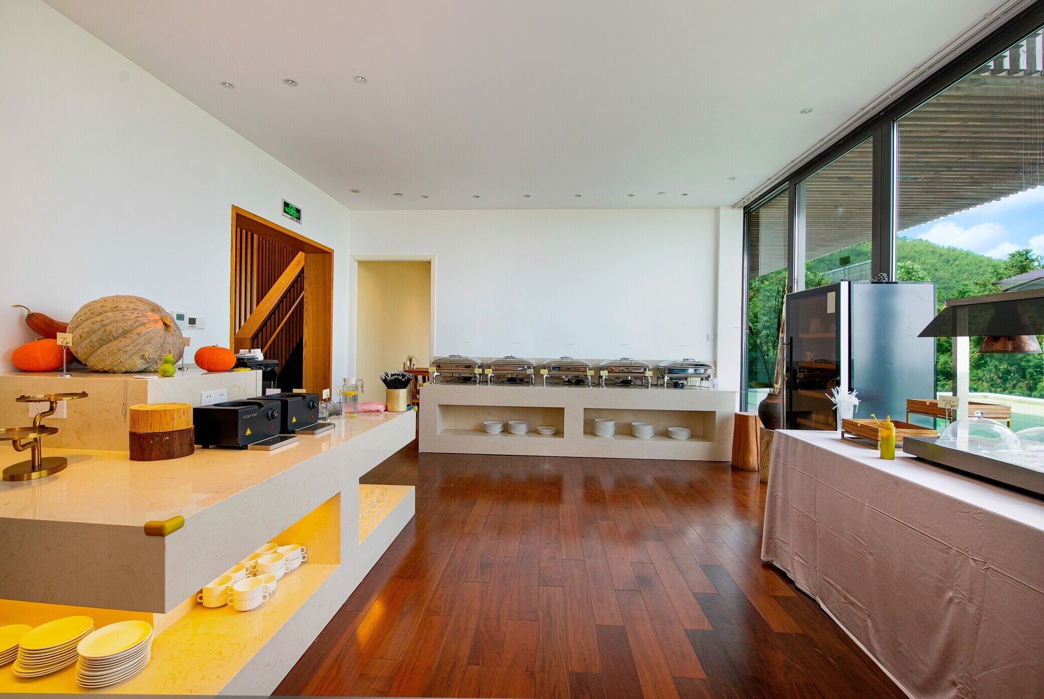 Een moderne keuken met een houten vloer, een inbouw aanrecht en een groot raam met uitzicht op de omgeving.