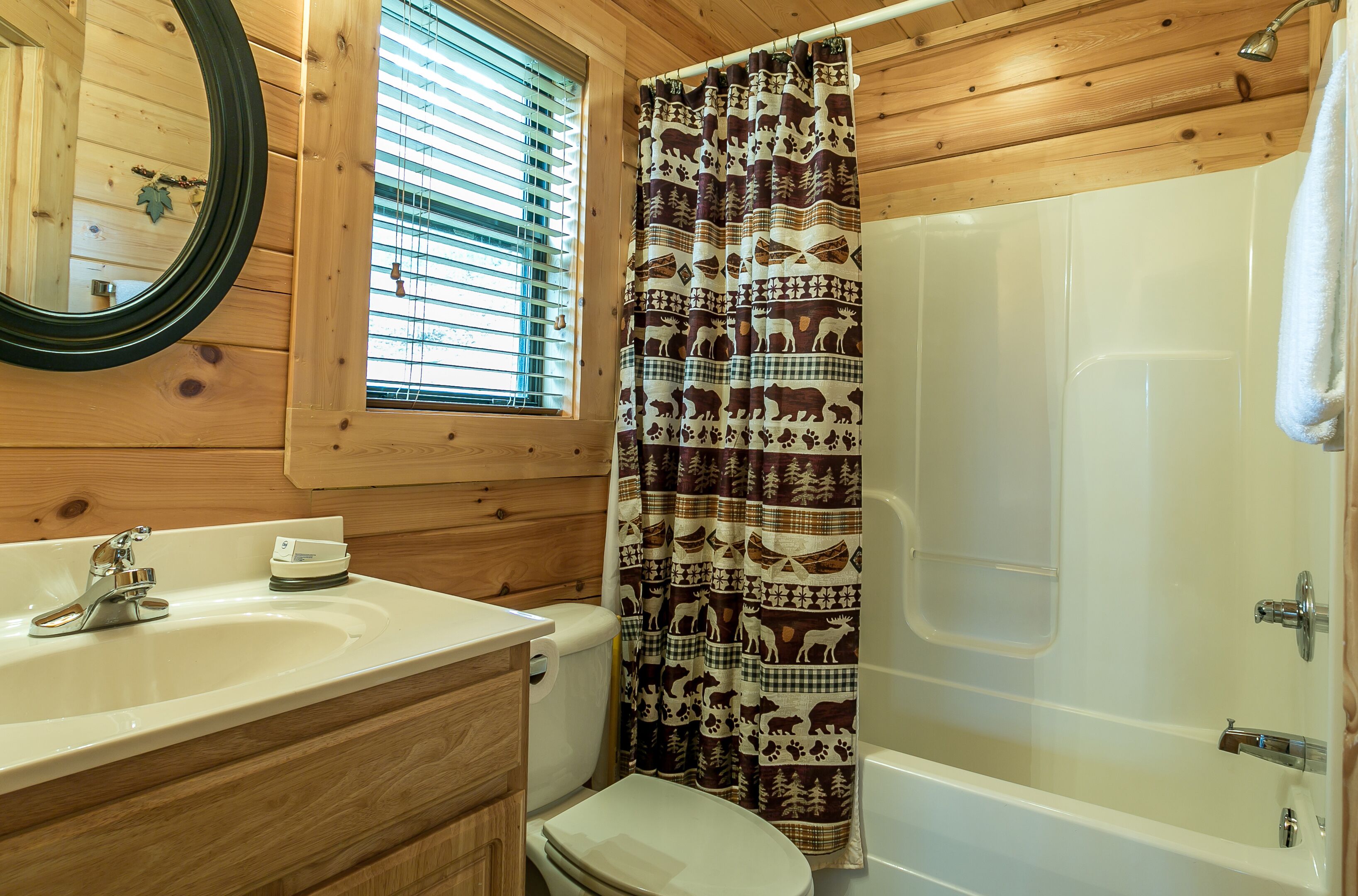 A wooden cabin bathroom with a sink, toilet, and shower.