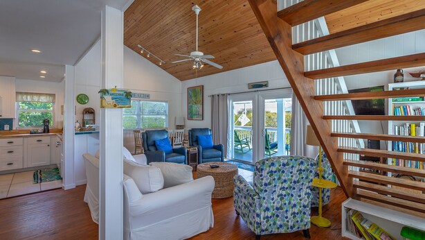 A spacious living room with a wooden ceiling, a staircase, a kitchen area, and a view of the outdoors. -  Just 200 Yards From The Beach. Pet friendly. Fenced back yard. (Saint George Island)