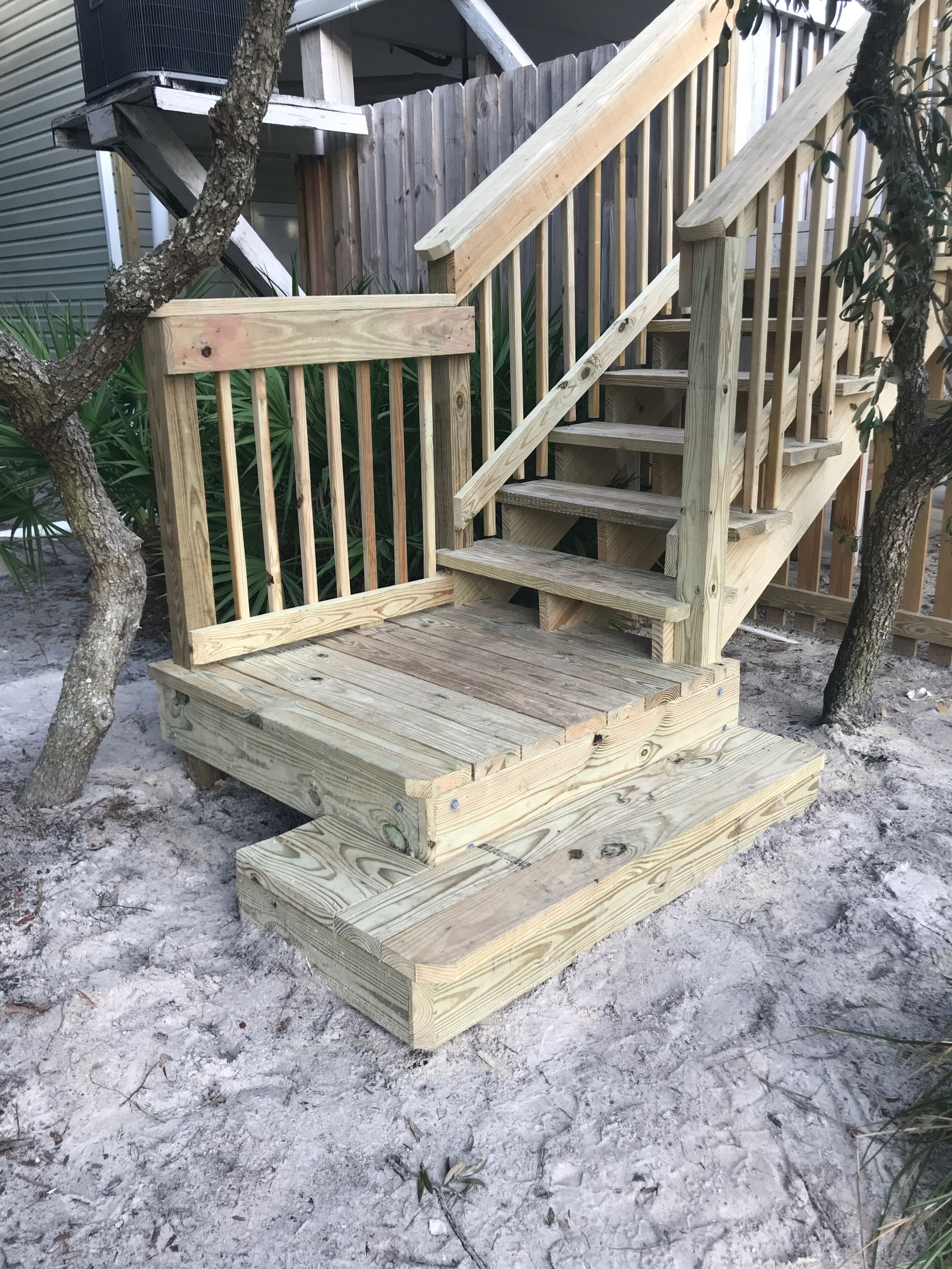 Una escalera de madera al aire libre que conduce a una terraza.