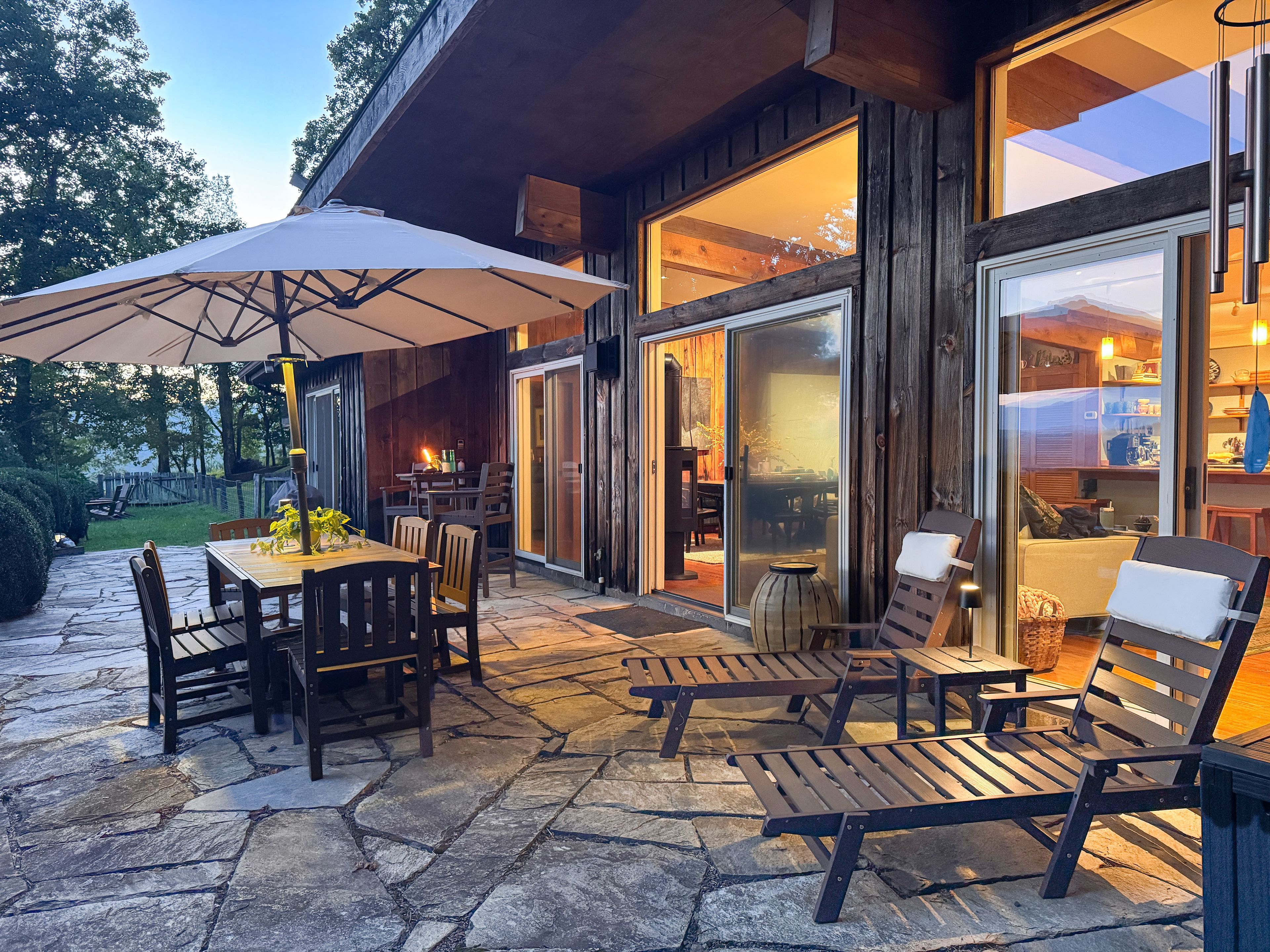 Spacious stone patio with dining, loungers, and warm indoor-outdoor charm